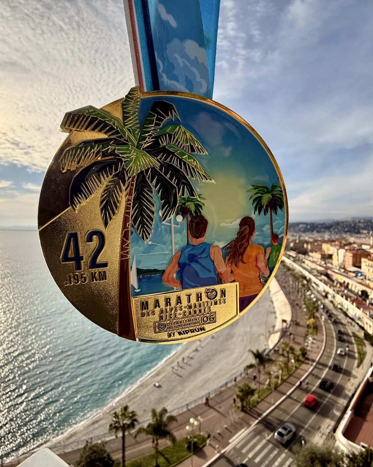 Medalla de finisher del Maratón Nice-Cannes 2025 con vista de Nice