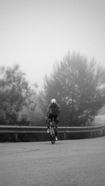 Radfahrer trainiert auf der Straße im Nebel
